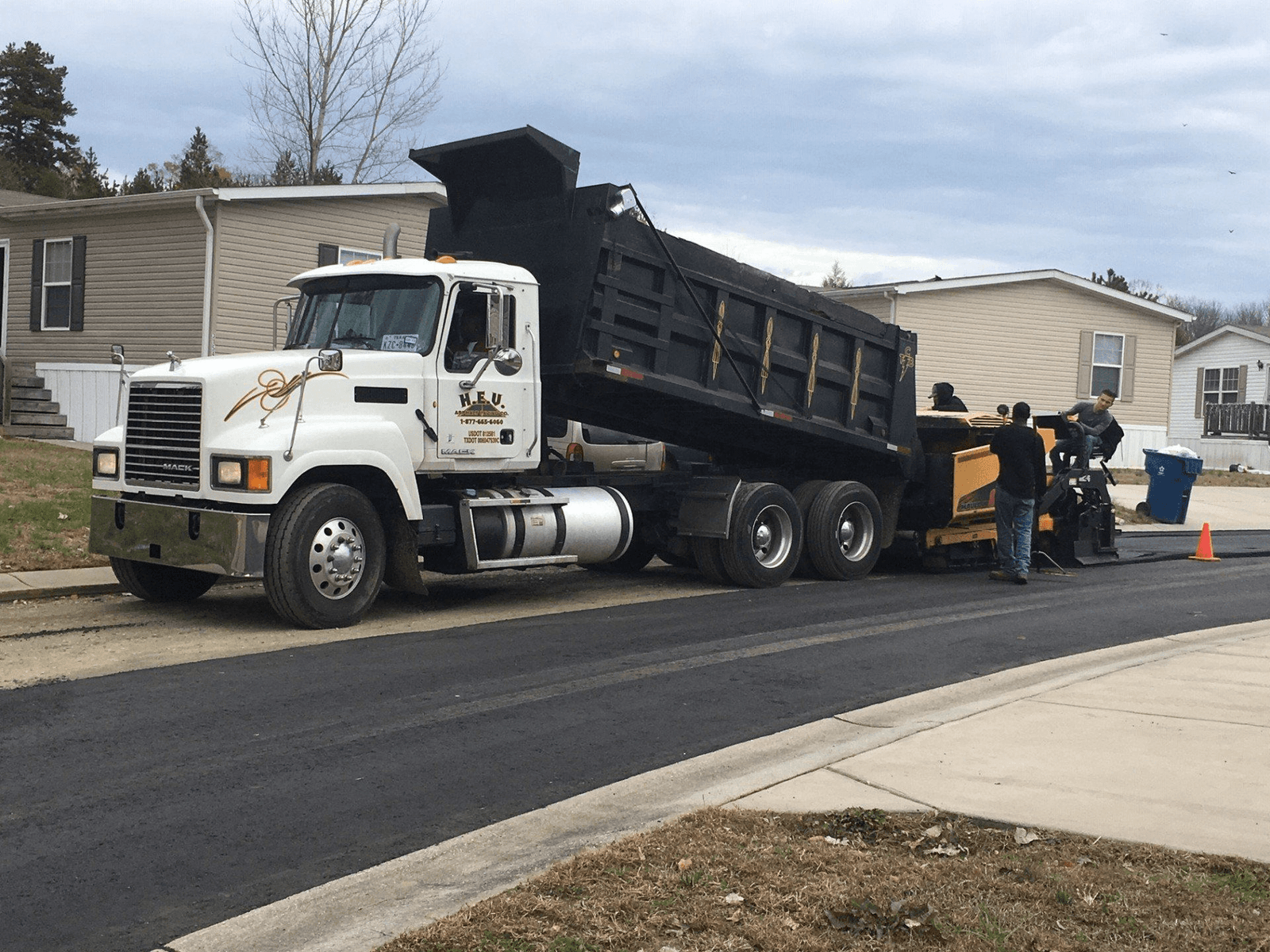 The HEV Asphalt Paving dump truck parked at a residential job site while the crew lays a new driveway