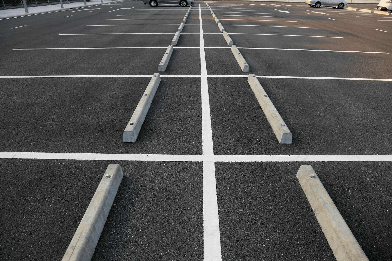 A crisp, freshly striped parking lot with clean white lines and parking bumpers